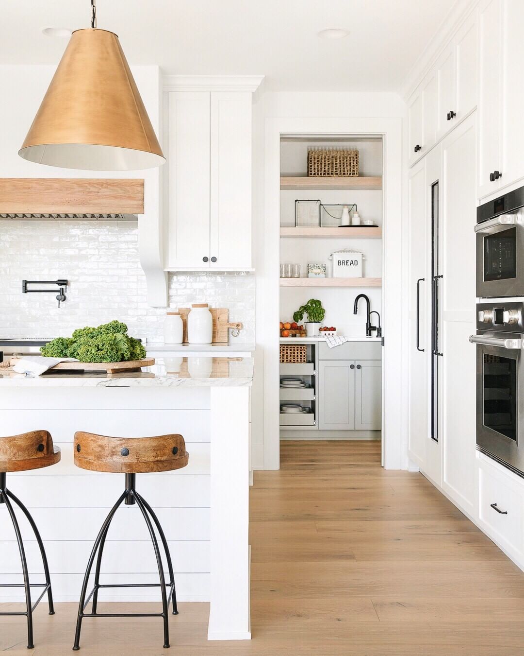 Brass Pendant Light above white kitchen island with bar stools via @briahammelinteriors