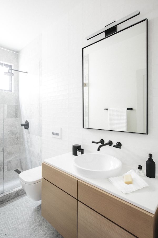 Scandinavian bathroom with marble tiling, black frame mirror and black faucet, via Luft