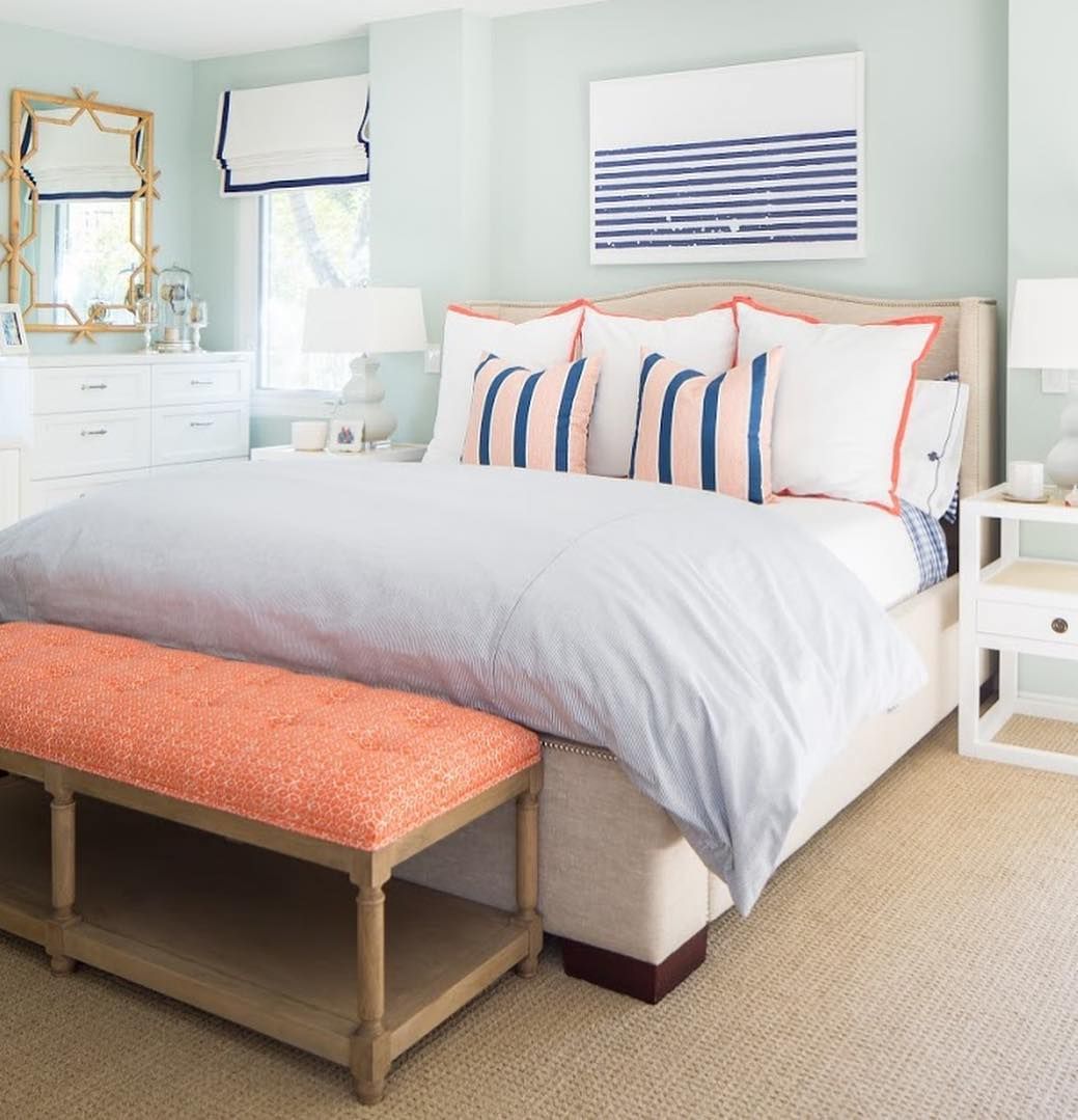Camera da letto costiera con accenti corallo e cuscini a righe via @agk_designstudio