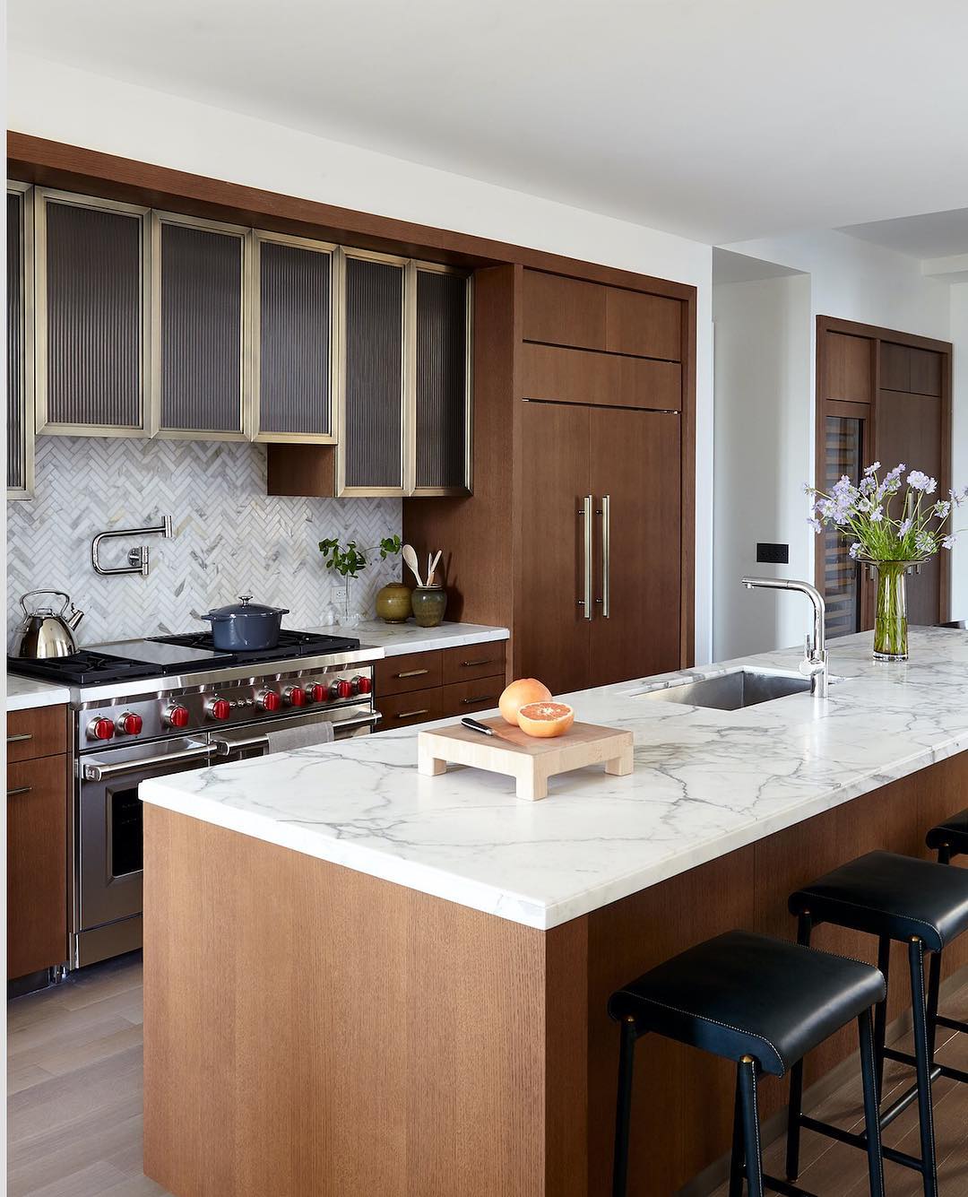 White marble and wood kitchens – Herringbone marble backsplash, dark wood kitchen island designed by Alyssa Kapito