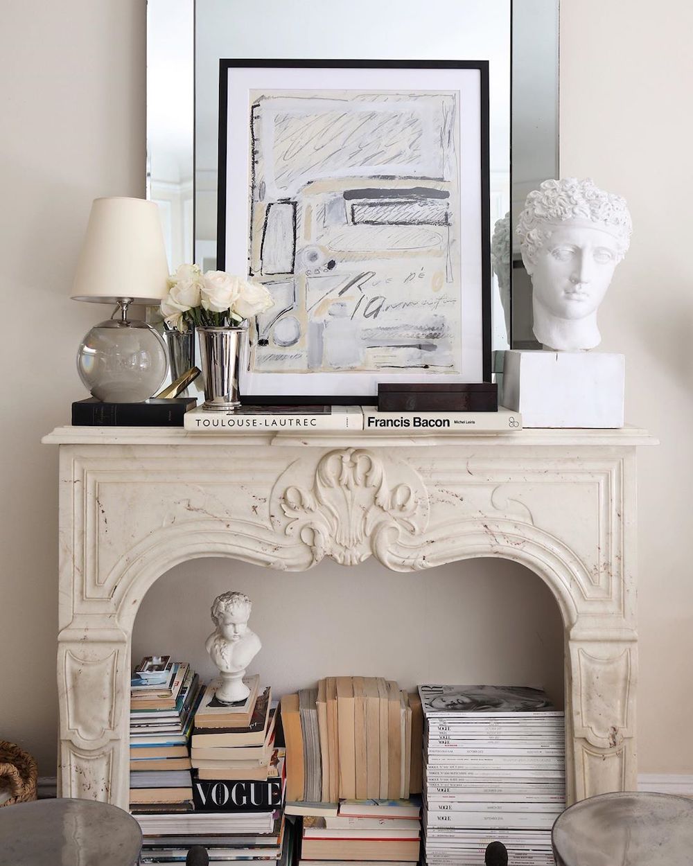 Josh Young white marble fireplace in living room with stacked books