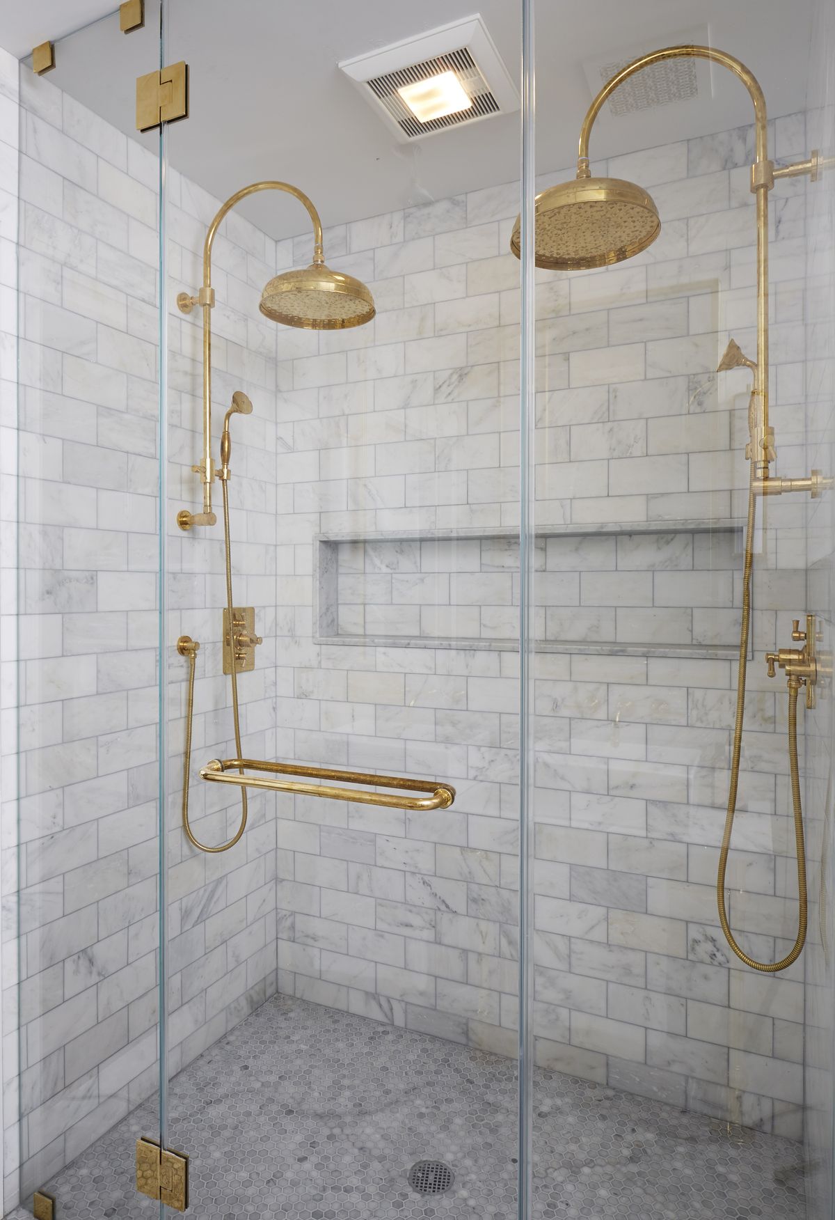 Master bathroom with double brass rain shower heads and marble subway tiles via Grant Davis Thompson