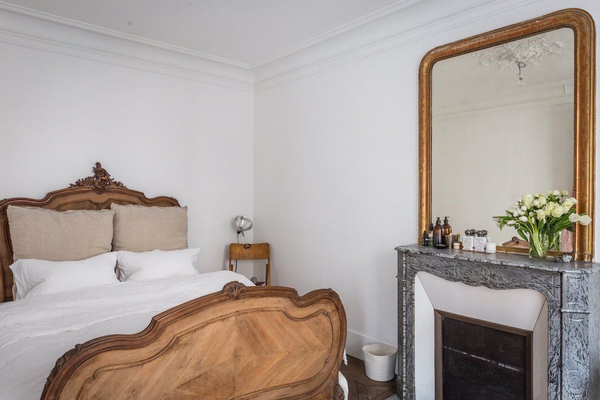 Parisian Bedroom with French country headboard and gold mirror via AptLafayette