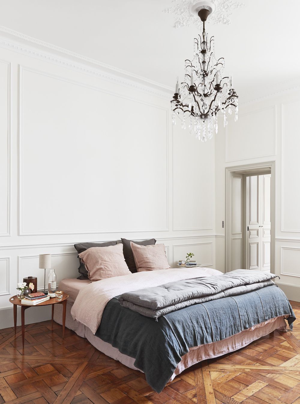 Parisian bedroom with faded linens and crystal chandelier via A + B Kasha