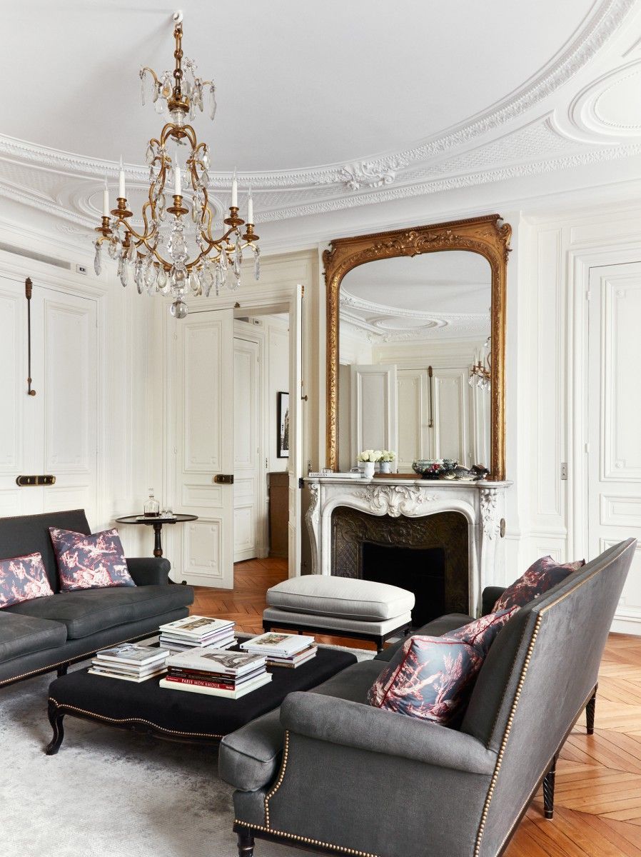 Parisian living room with crystal chandelier and ottoman as coffee table via A+B Kasha