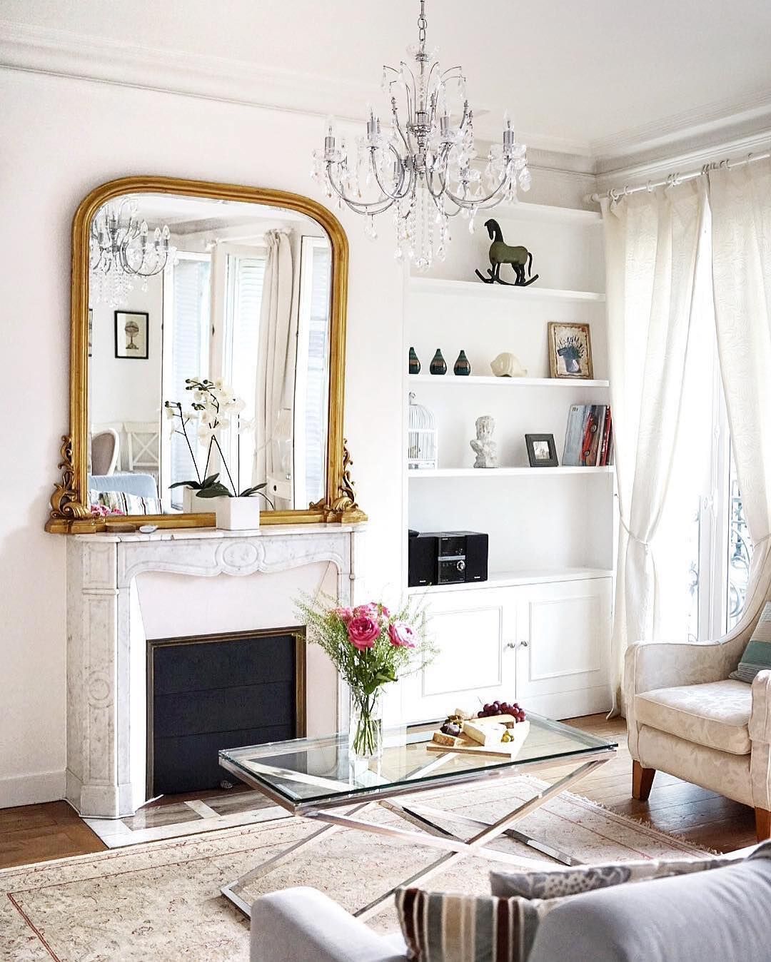 Parisian living room with gold mirror and glass coffee table via @roxannematiz