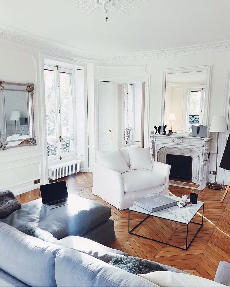 Parisian living room with marble coffee table and white slipcovered accent chair via @tashoakley