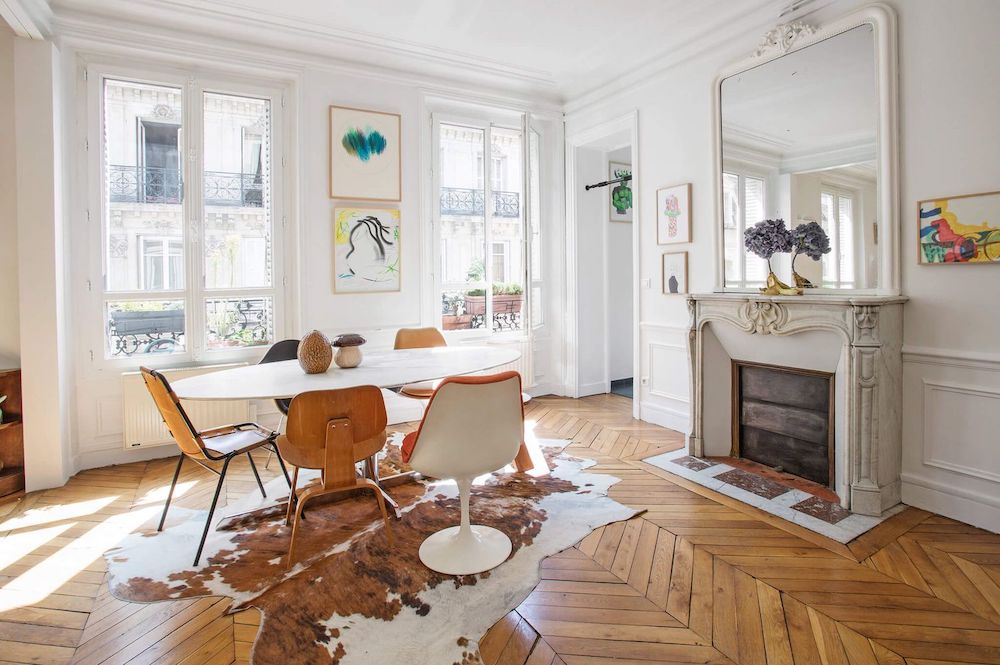 Parisian dining room with Cowhide rug and mismatched dining chairs via Havenin Saint Germain