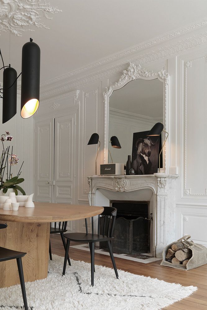 Parisian dining room with Brown table, black chairs, and white rug via Revistaad.es