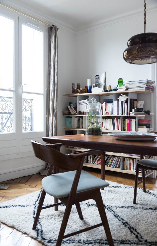 Parisian dining room with brown Mid-century modern chairs and bookshelf via The Socialite Family Sabina Socol