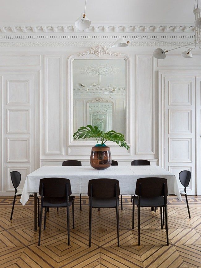 Traditional Parisian dining room design with Jean Prouvé Chairs, Serge Mouille Lamp, black dining chairrs, white tablecloth via Stephan Julliard pour le Studio Razavi