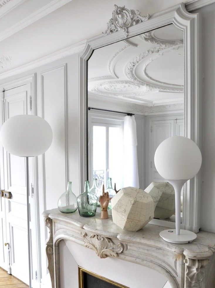 Parisian fireplace with modern white table lamp via Marie-Claire Fresquet