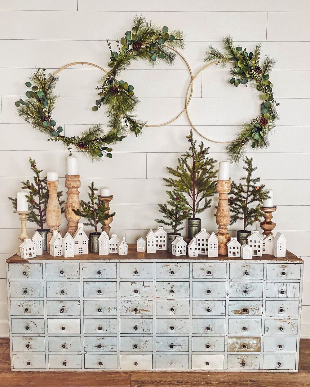 Farmhouse winter console table decor with white houses and evergreen hoops via @cottonstem