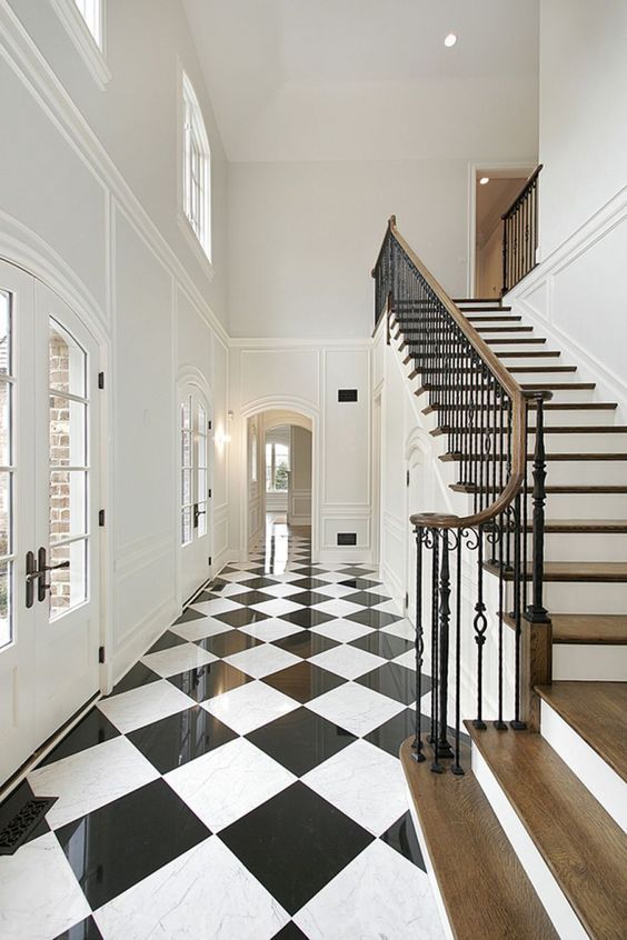 Black and white checkered tile floors in long hallway below staircase