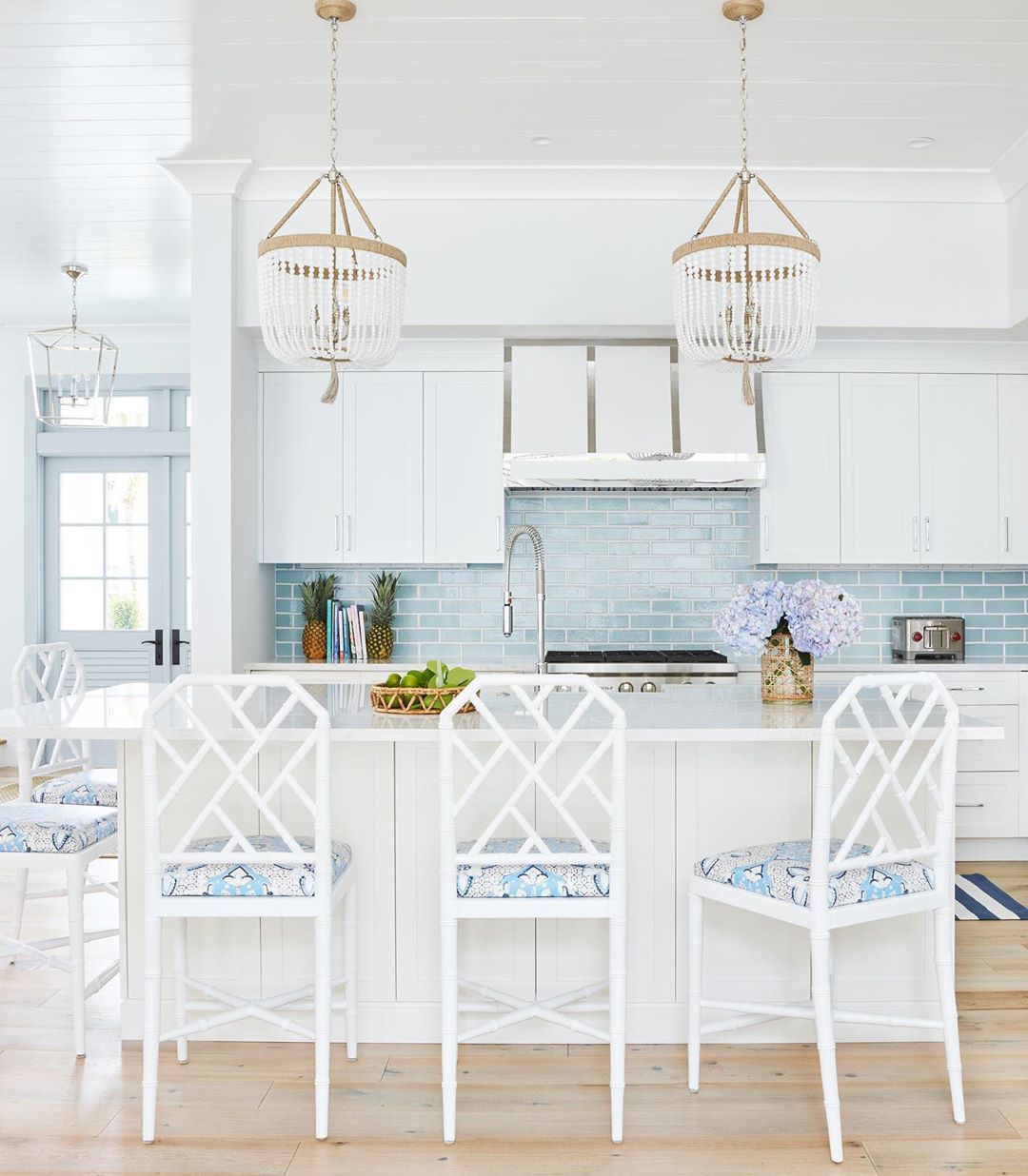 Coastal Kitchen With White Rattan Counter Chairs And Sea Blue Subway Backsplash Tile Via @karahebertinteriors 