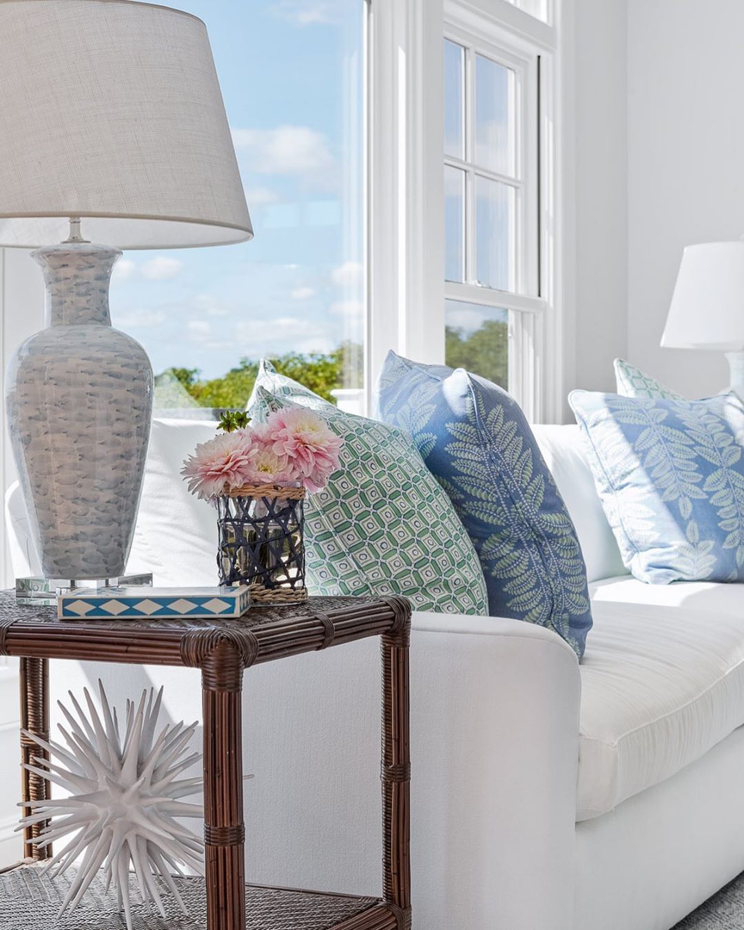 Coastal Living Room with White Sofa and Brown Rattan Side Table via @digsdesignco