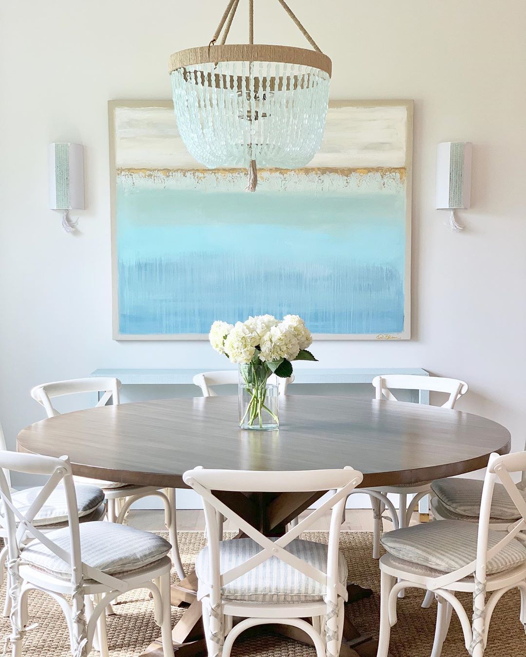 Coastal Dining Room with Abstract Beach Art, beaded chandelier, and Crossback Chairs via @karahebertinteriors