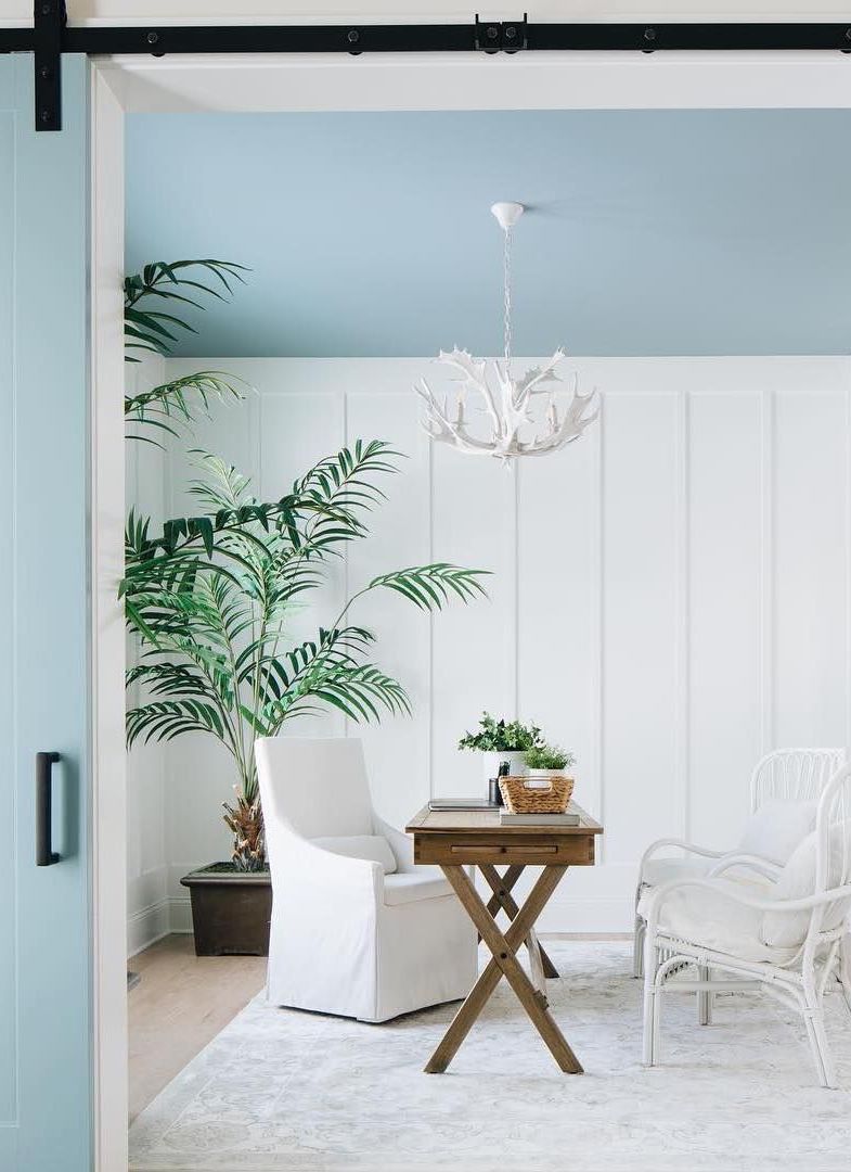 Coastal Office with Blue Ceiling, white rattan accent chairs, wood desk, white slipcover arm chair, corner palm plant via @timbertrailshomes