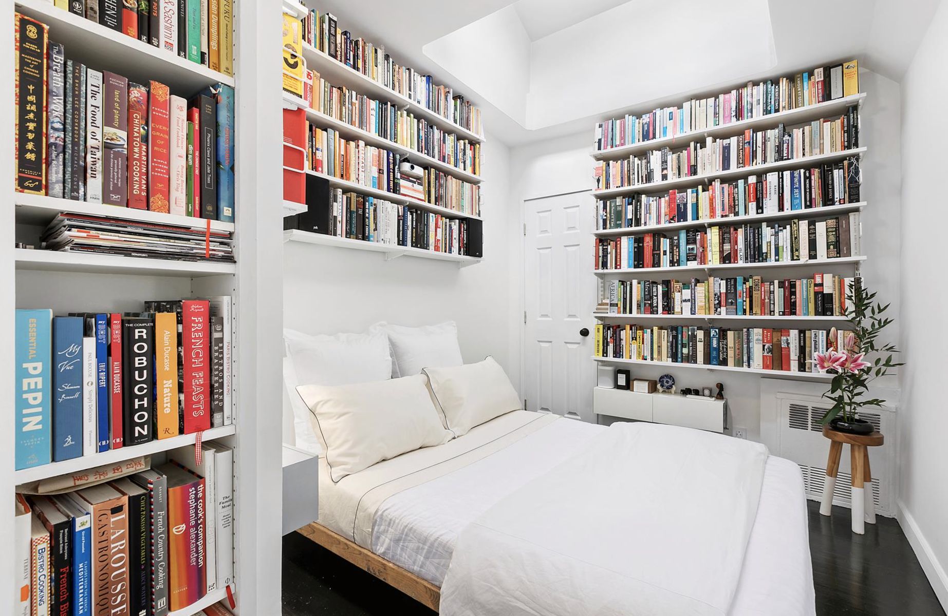 Bedroom with Three walls of Bookshelves floor to ceiling via Apartment Therapy