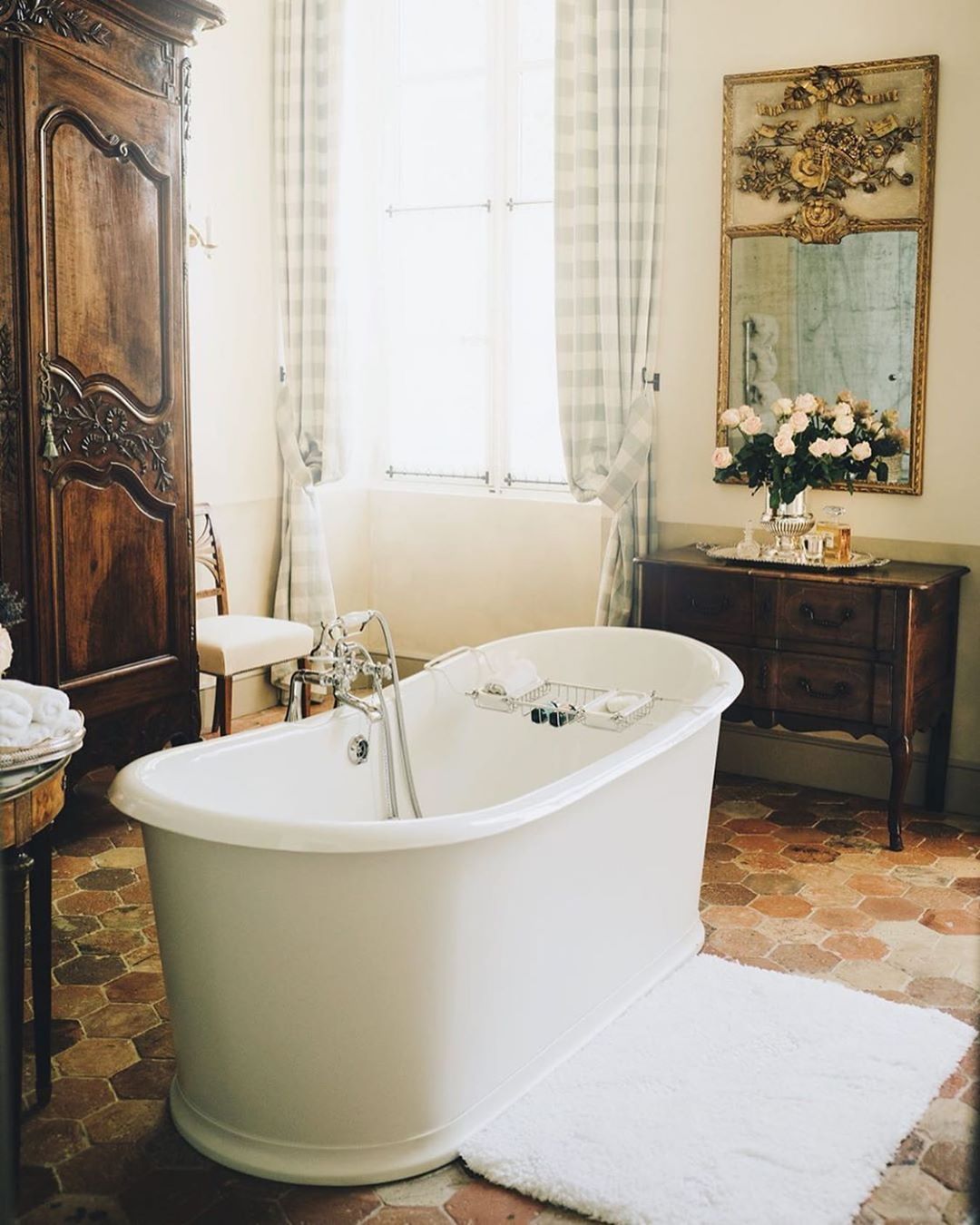 French Country Bathroom With White Freestanding Tub And Brown Vintage Armoire Via @provencepoiriers 