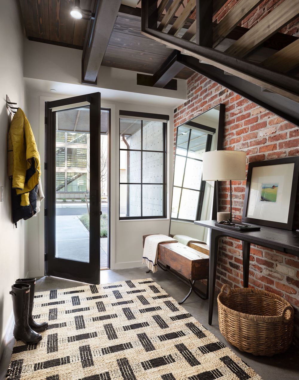 Industrial Entryway Design with Brick Wall and Wood Bench via Dana Webber Design Group