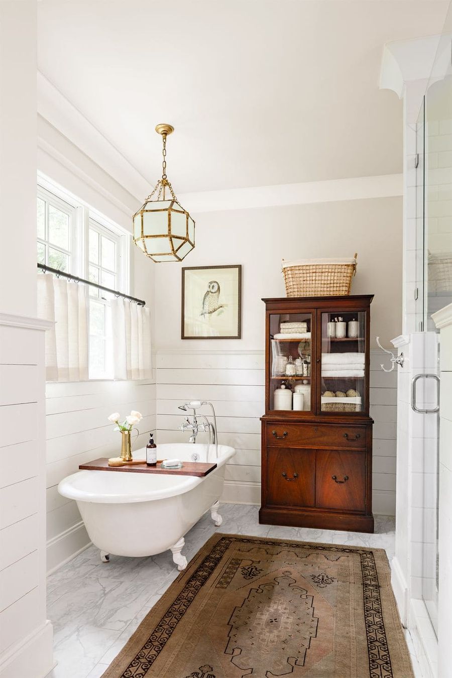 Wooden Storage Hutch in Farmhouse Bathroom with Clawfoot Tub and Vintage Rug via Lincoln Barbour Country Living