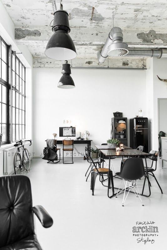 Réfrigérateur Smeg noir dans une salle à manger industrielle avec des accents en métal noir