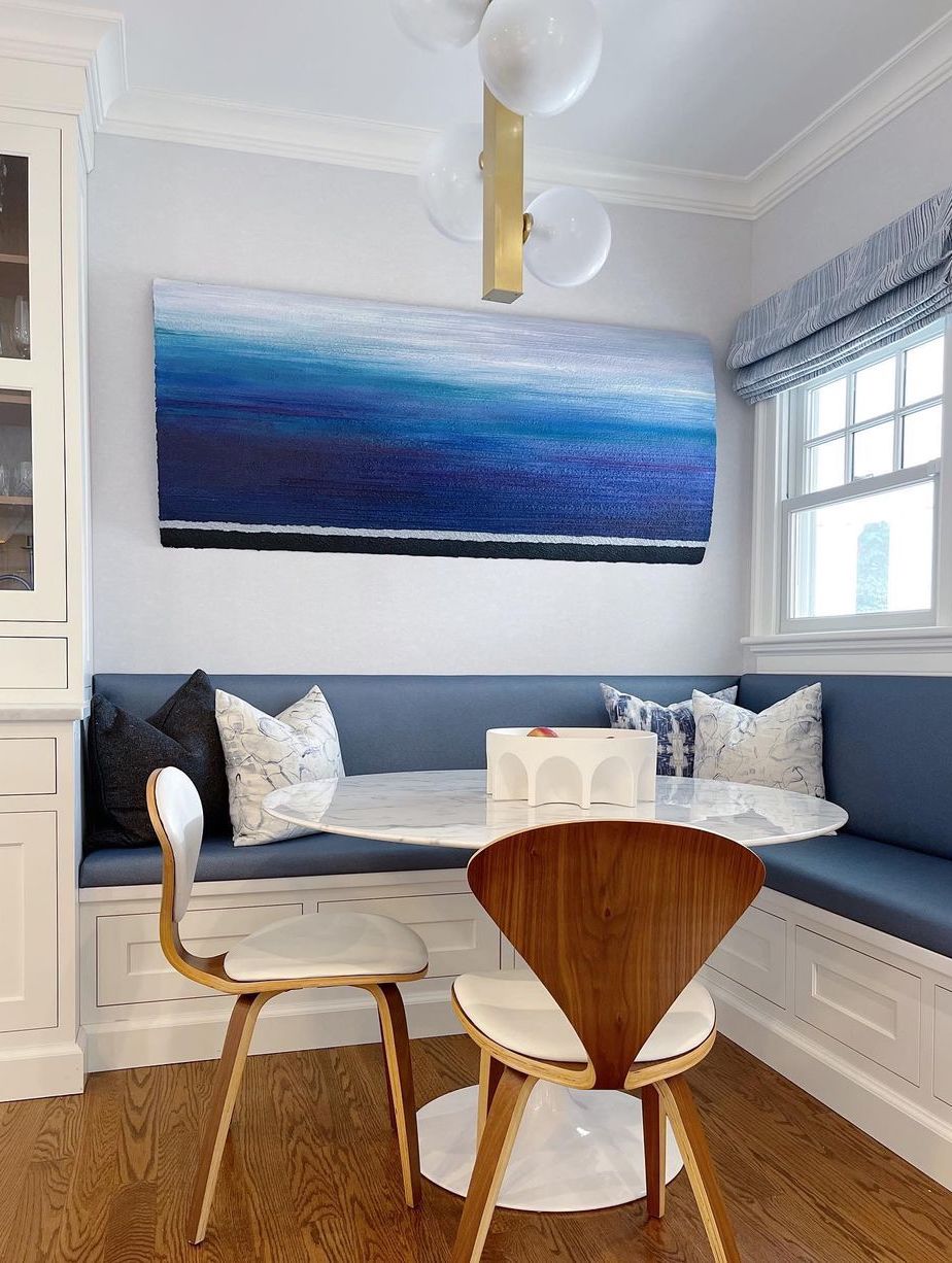 Coastal breakfast nook with mid-century modern chairs and built-in banquette navy cushion