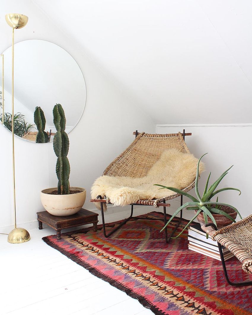 Colorful textile floor rug, a wicker egg chair, a brass floor lamp, a cactus, and a faux fur throw in Bohemian Reading Nook via @ball_and_claw_vintage