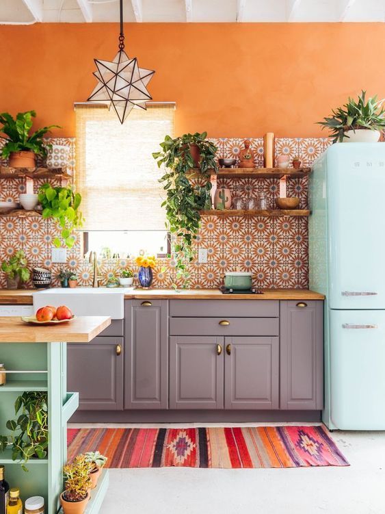 Orange accent wall with floral boho backsplash tiles and blue fridge via the Junglalow