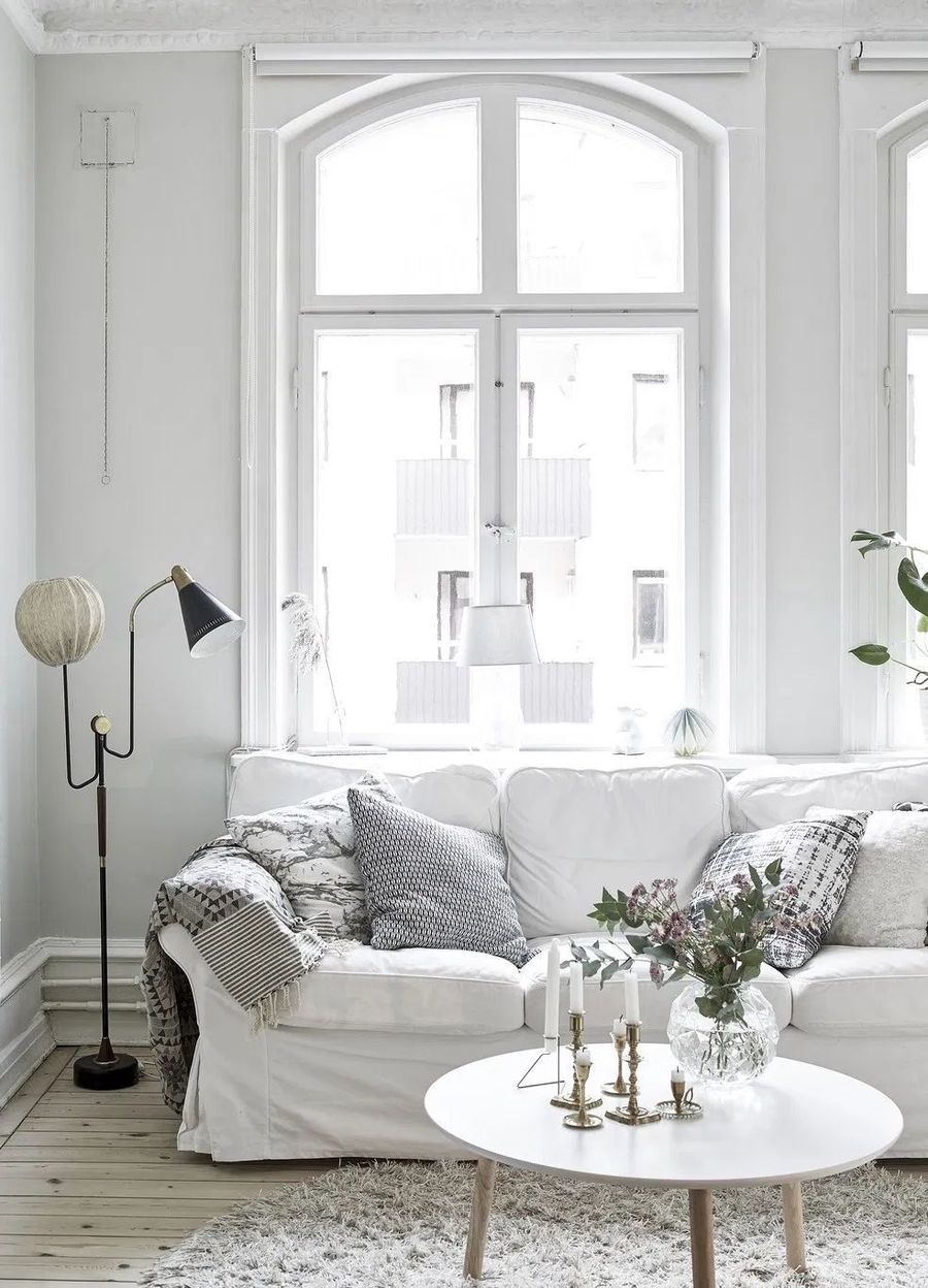 White Slipcovered Sofa and White Coffee Table in Scandinavian Living Room with nordic inspired design via entrancemakleri