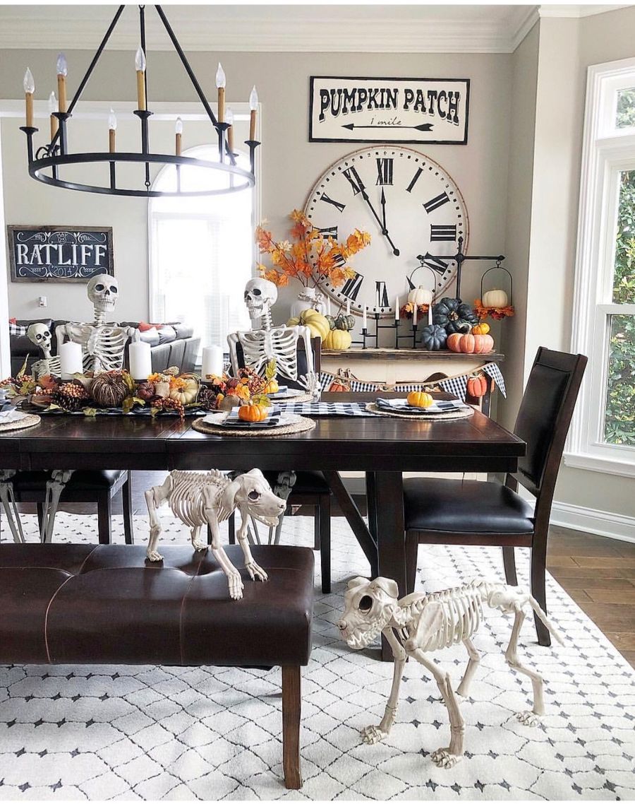 Farmhouse Halloween Decor Skeletons Sitting on Dining Room Chairs via jennaratliffdesigns